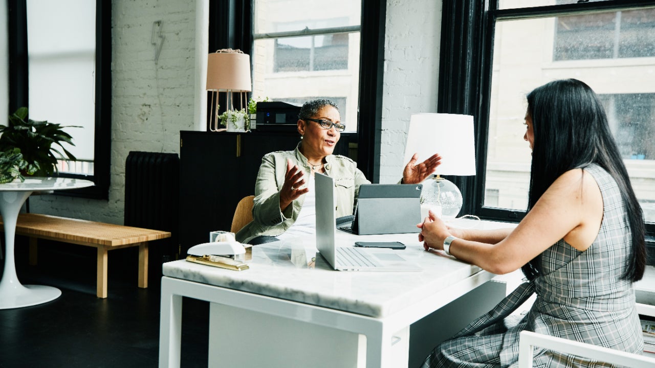 A financial advisor works with a woman client from her desk