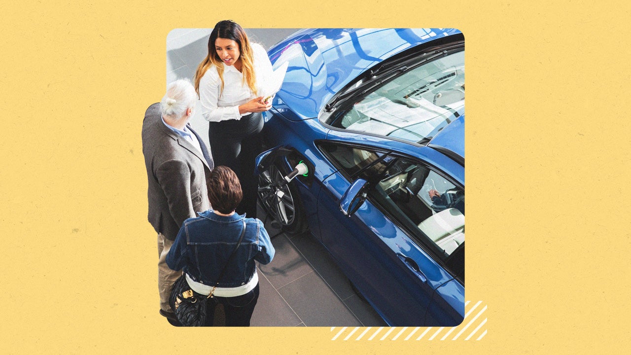 Two people looking at a blue car while dealership agent talks about it