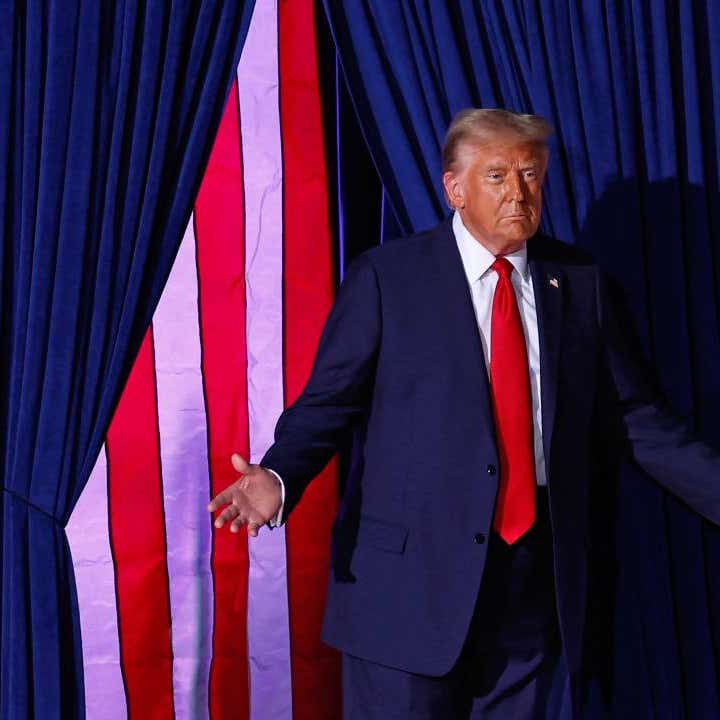 President-elect Donald Trump onstage at a rally with American flags displayed behind him.